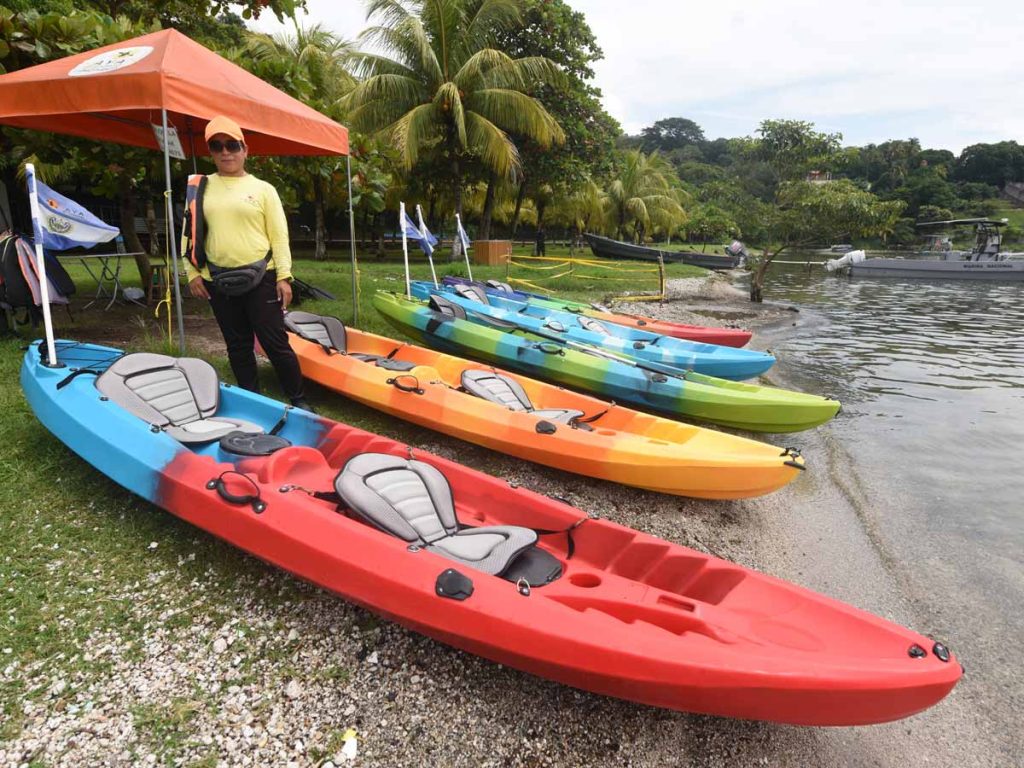 Kayaks coloridos alineados en la orilla del Lago de Ilopango listos para alquiler turístico