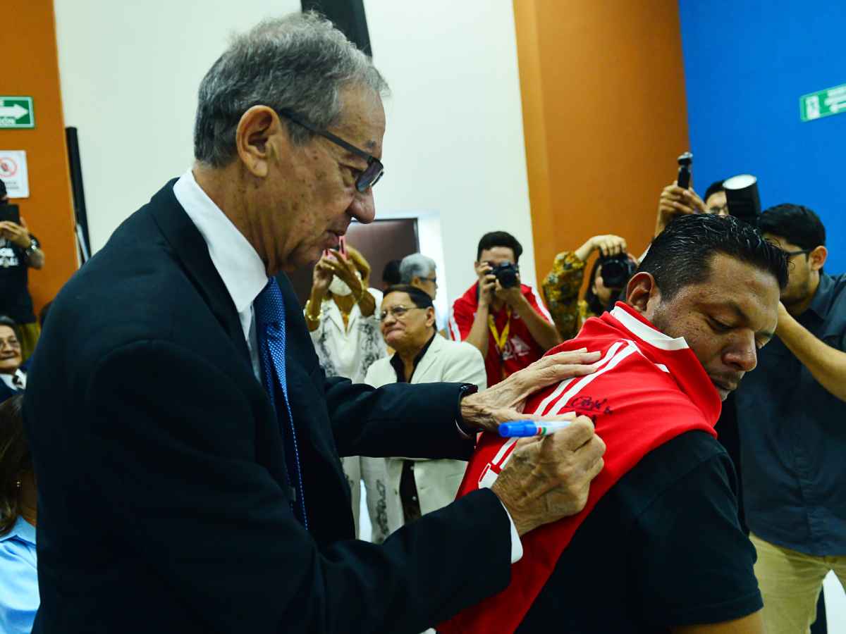 Mauricio «Pipo» Rodríguez firmando con una pluma una camiseta de la Universidad de El Salvador para Pedro Lemus.