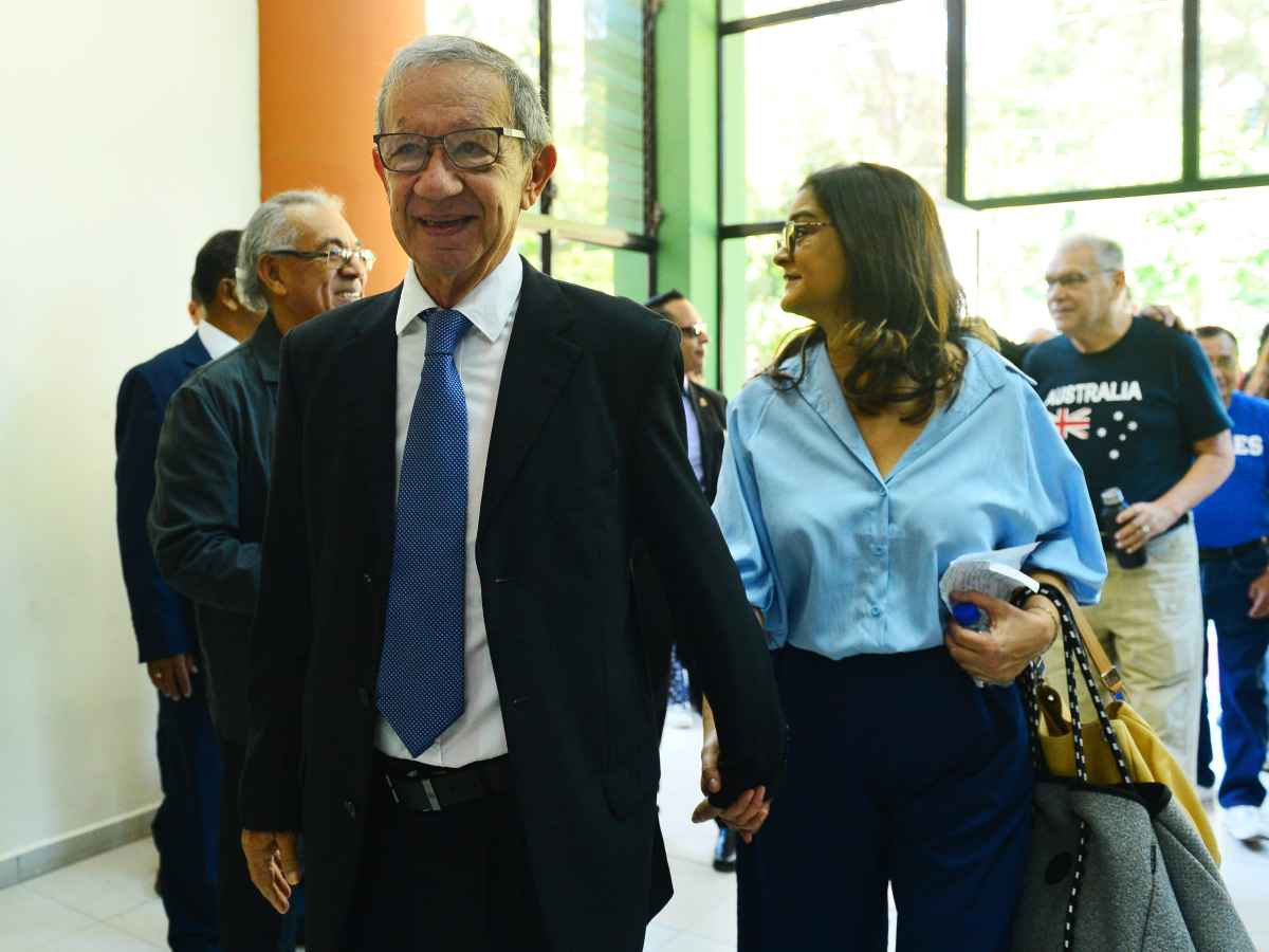 Mauricio «Pipo» Rodríguez ingresa caminando a un auditorio de la UES junto a su hija mayor para el homenaje.