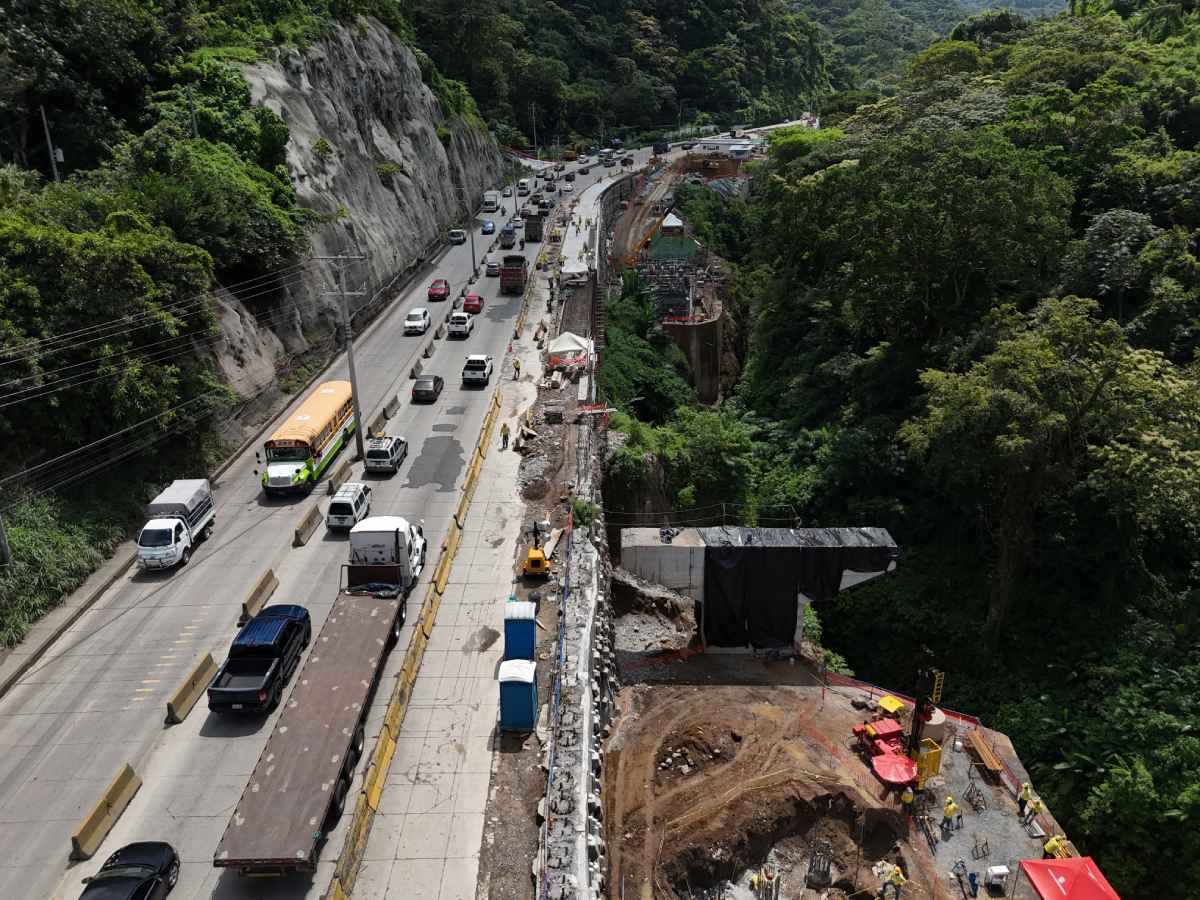 Maquinaria pesada trabajando en la estabilización de un talud rocoso junto a la carretera.