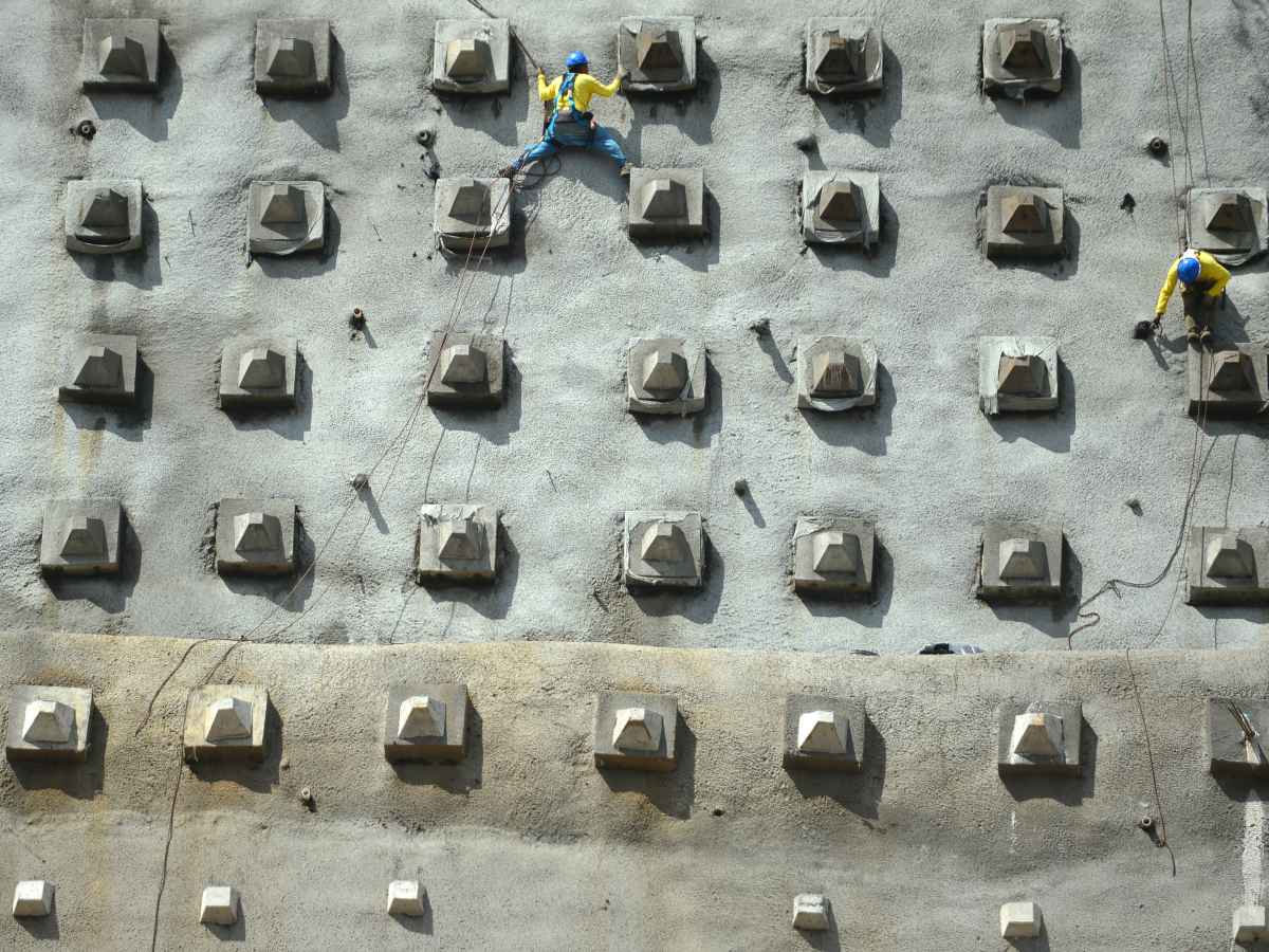 Trabajadores realizando tareas de construcción y refuerzo sobre el muro de contención en Los Chorros.