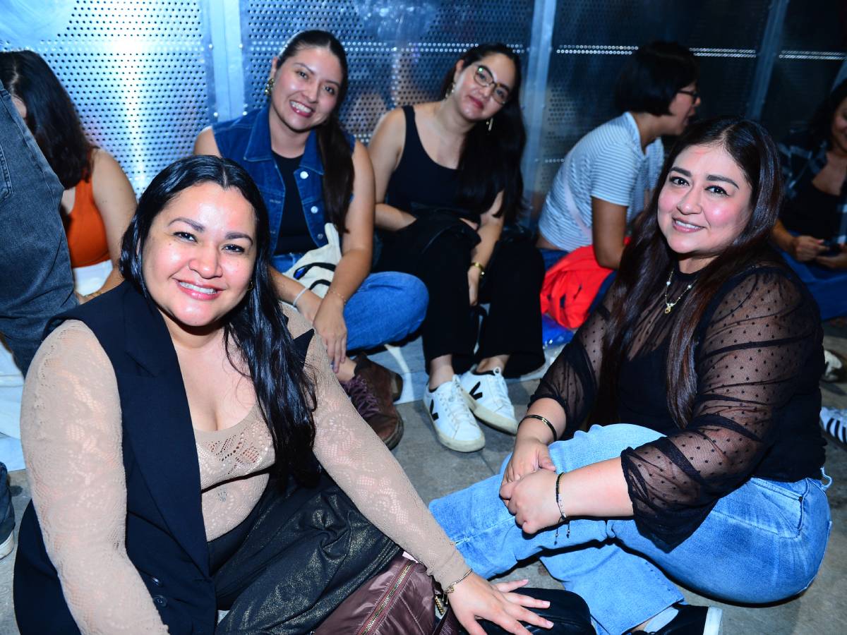 Cuatro asistentes al concierto sonriendo a la cámara en el recinto del evento, ubicadas de izquierda a derecha.
