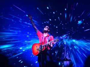 Fotografía del cantante Manuel Medrano en el escenario del complejo Be Sport en El Salvador, rodeado de luces y fans.