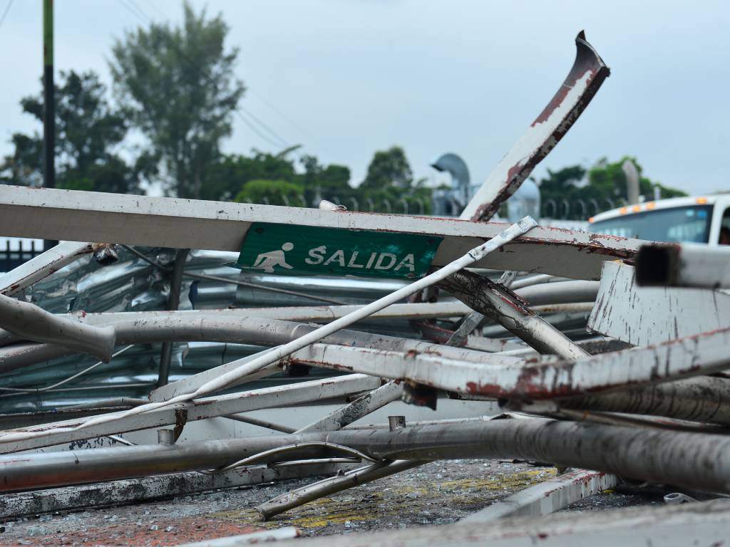 rafía de primer plano que enfoca un cartel con la palabra "Salida", dañado y aplastado entre piezas de hierro retorcido tras la demolición de la terminal.