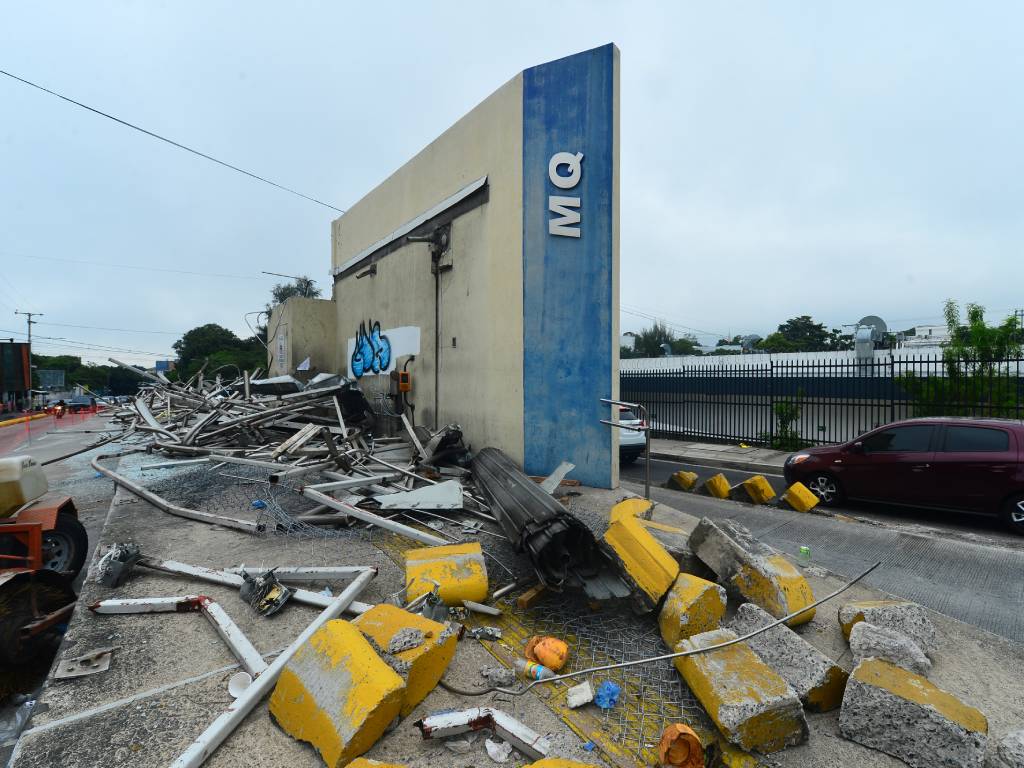 Fotografía que muestra únicamente en pie una sección de pared de la entrada principal de la estación del SITRAMSS en demolición.
