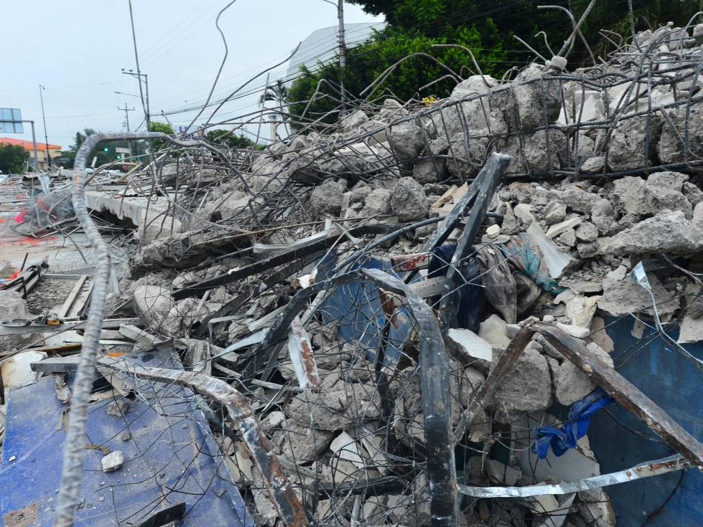 Fotografía de primer plano que muestra fragmentos de concreto y varillas de hierro retorcidas amontonadas en el suelo tras la demolición de la estación del SITRAMSS.
