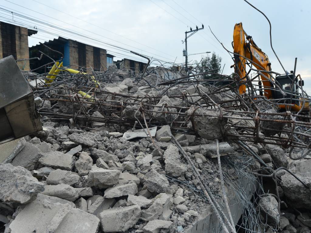 Fotografía de una excavadora destruyendo las paredes y vigas de hierro de la estación del SITRAMSS, acumulando escombros en el suelo.