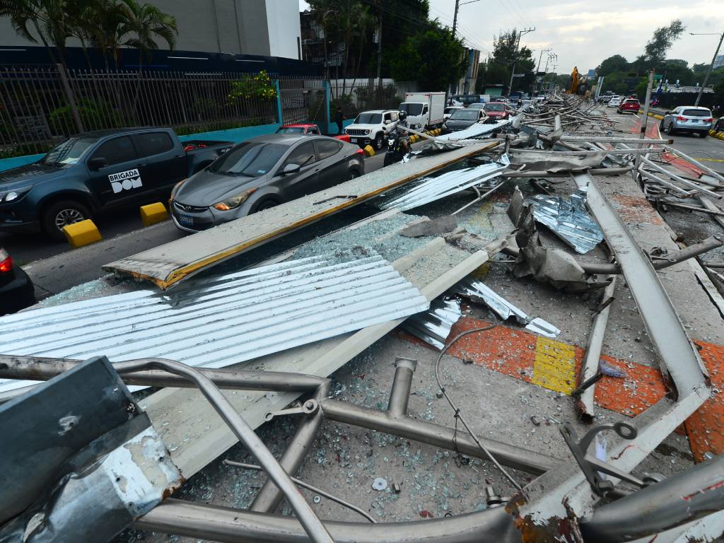 Fotografía de una cuadrilla de trabajadores y herramientas pesadas demoliendo la estructura metálica y el techo de la estación doble del SITRAMSS en San Salvador.