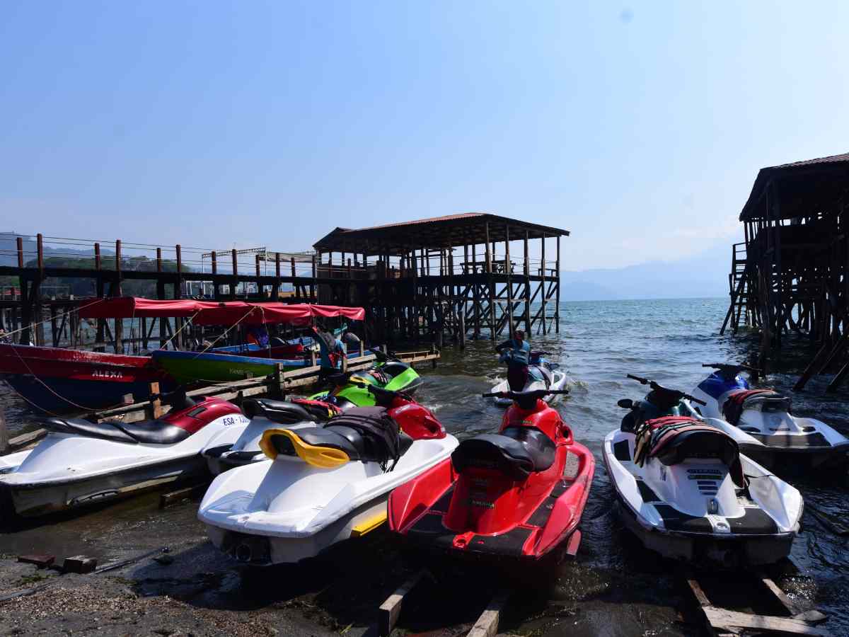 Turistas disfrutando de actividades acuáticas y gastronomía a orillas del cristalino Lago de Coatepeque.