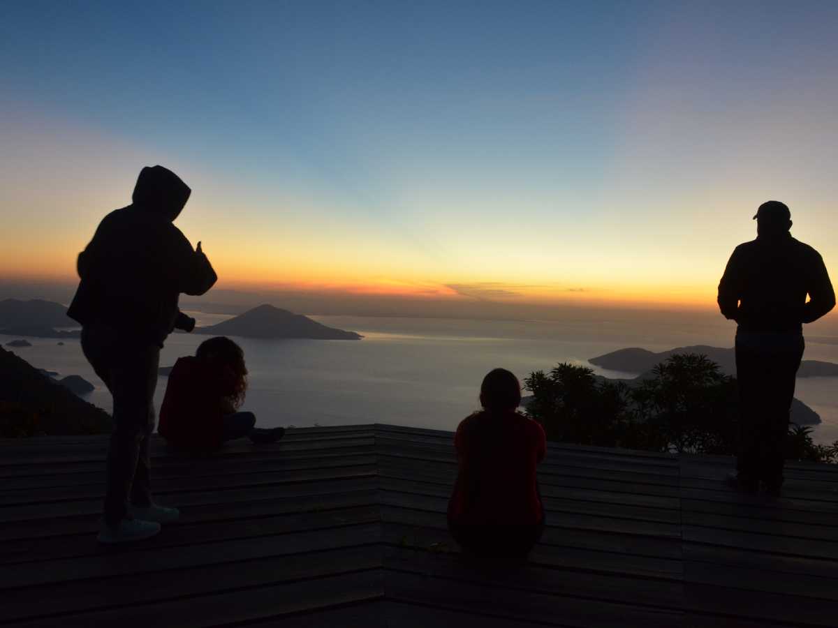 Vista panorámica del sol naciente emergiendo sobre el mar frente a la elevada cima del volcán.