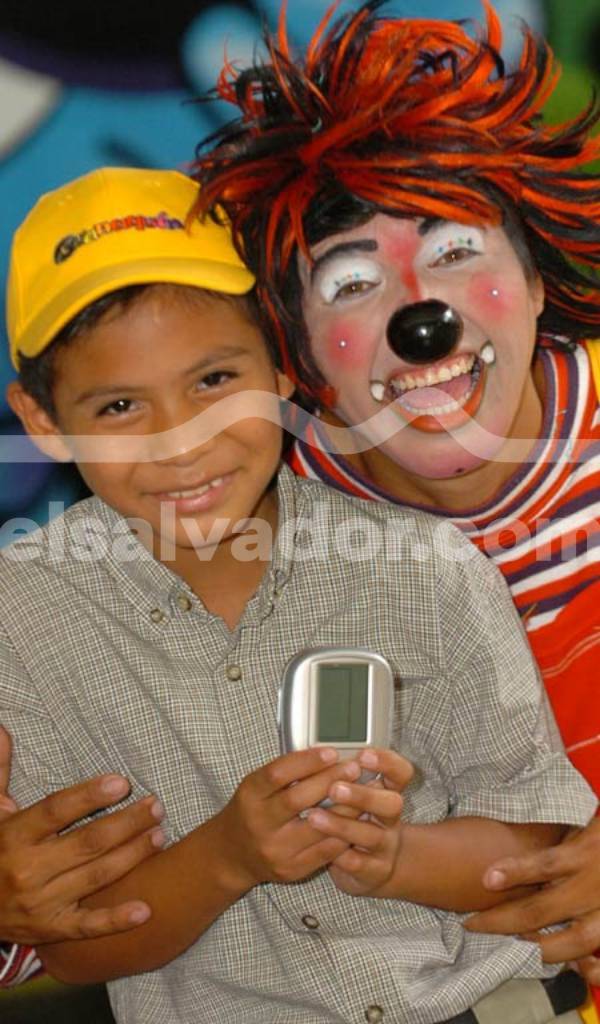 Payasos sonrientes animando una fiesta de cumpleaños rodeados de niños en un parque de atracciones.
