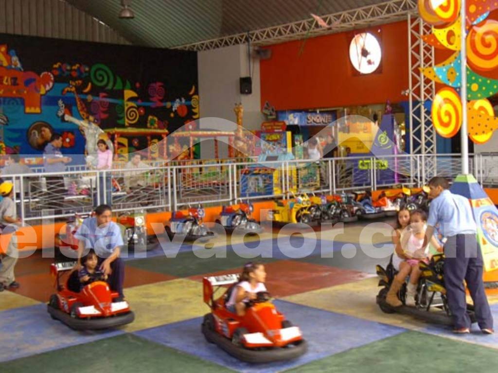 Niños pilotando los tradicionales carros chocones dentro del parque de atracciones.