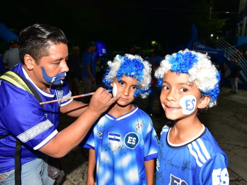Dos pequeños aficionados lucen pelucas azul y blanco y pintura en el rostro antes del partido de la Selecta.