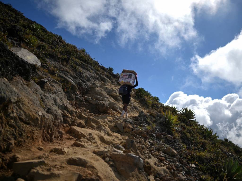 Vendedor ambulante de paletas en el sendero hacia la cumbre del volcán ofreciendo helados a los caminantes.