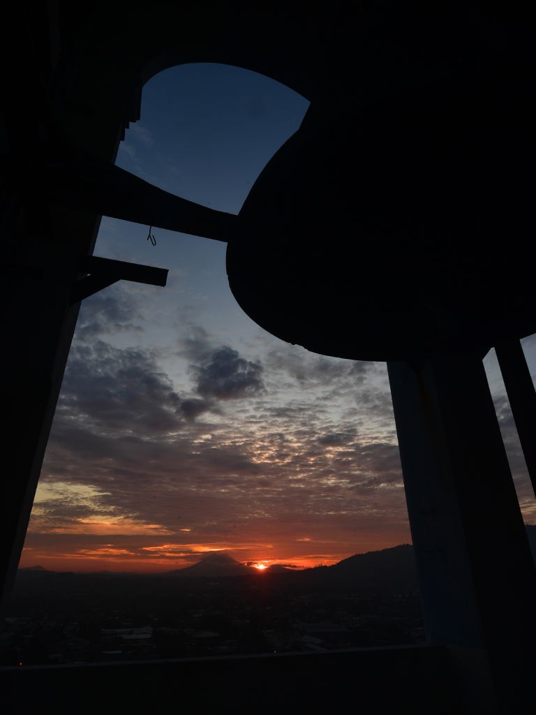 La imponente silueta de la campana enmarca el primer destello del sol naciente sobre la capital.