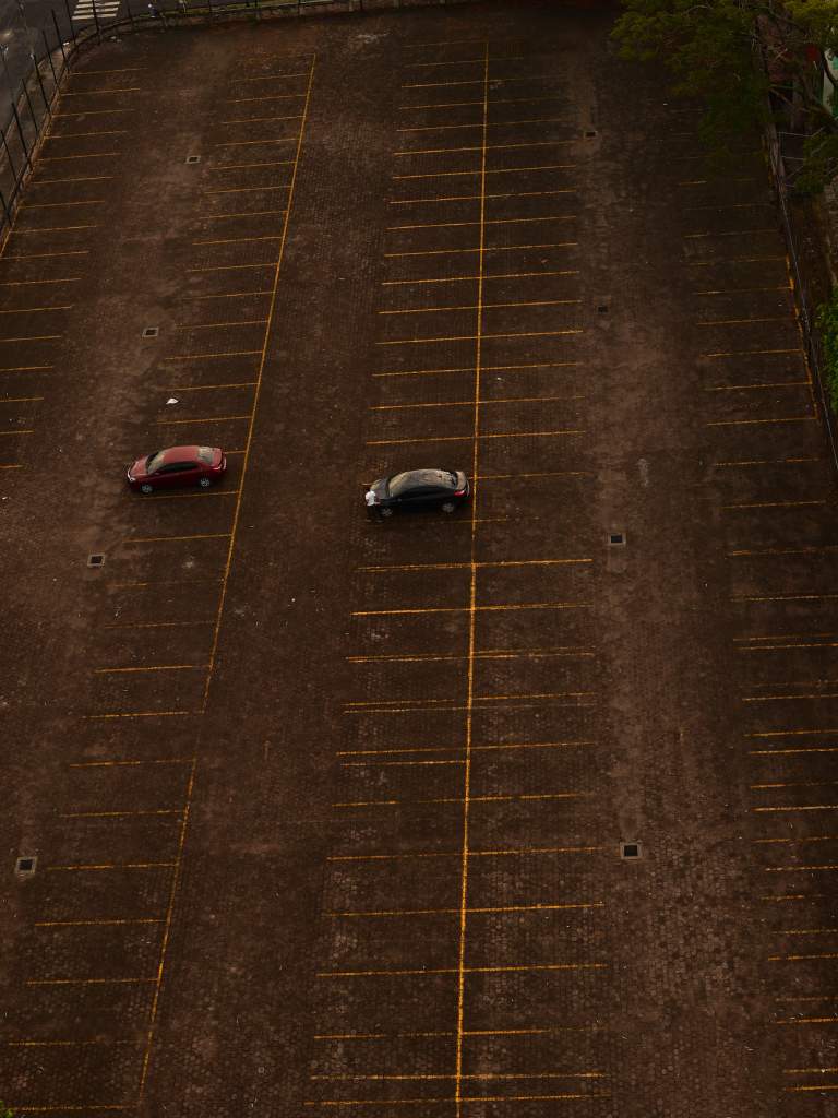 Vista cenital del estacionamiento aún casi vacío bañándose con la tibia luz matutina.