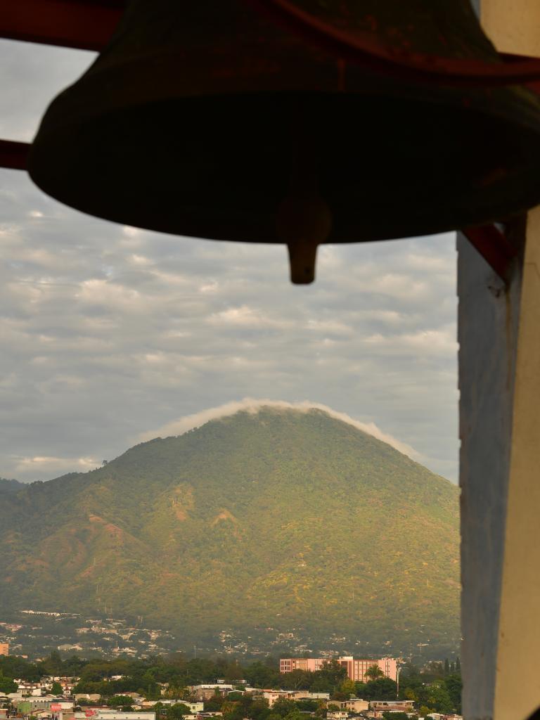 El perfil del volcán cubierto de nubes se enmarca perfectamente bajo el contorno de la gran campana.
