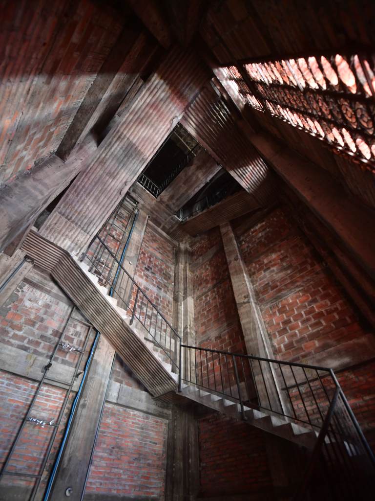 Las líneas de la escalera del interior del campanario suben hacia la luz, enmarcadas por paredes de ladrillo visto.