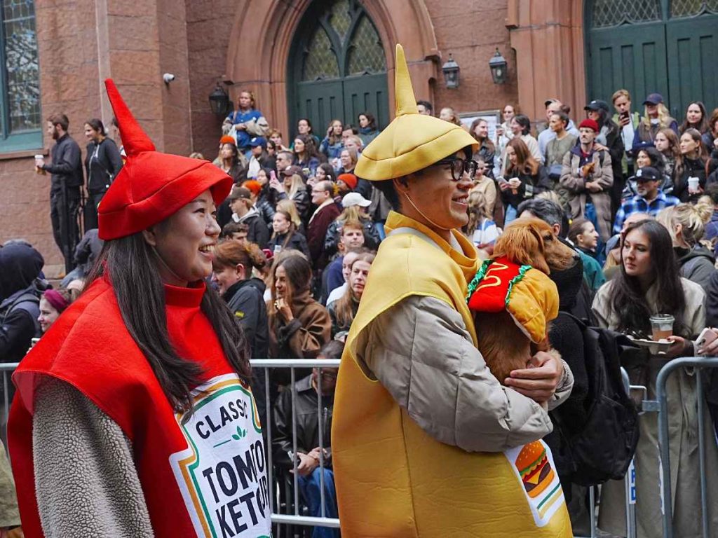 Una pareja y su perro, disfrazados de ketchup, mostaza y hot dog participan en el desfile canino de Halloween en Manhattan.