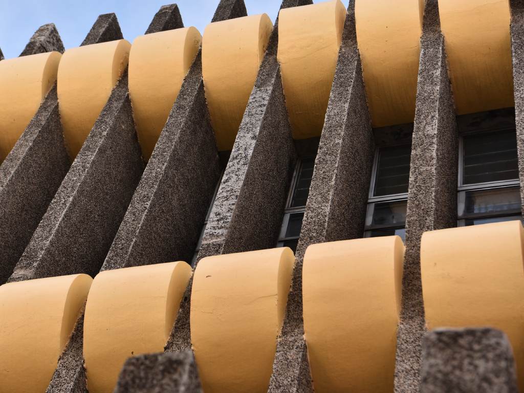 Detalle cercano que contrasta la rugosidad del hormigón martillado con el acabado liso de los volúmenes amarillos.