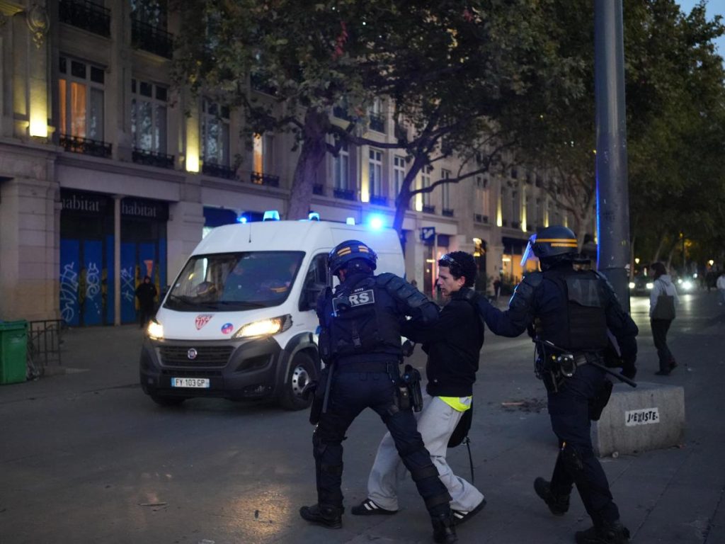 Agentes de policía escoltan a una persona por una calle cerca de un vehículo de emergencia en París, Francia, el 18 de octubre de 2026.