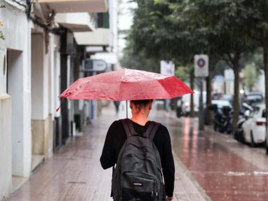 Una mujer se protege de la lluvia con un paraguas.