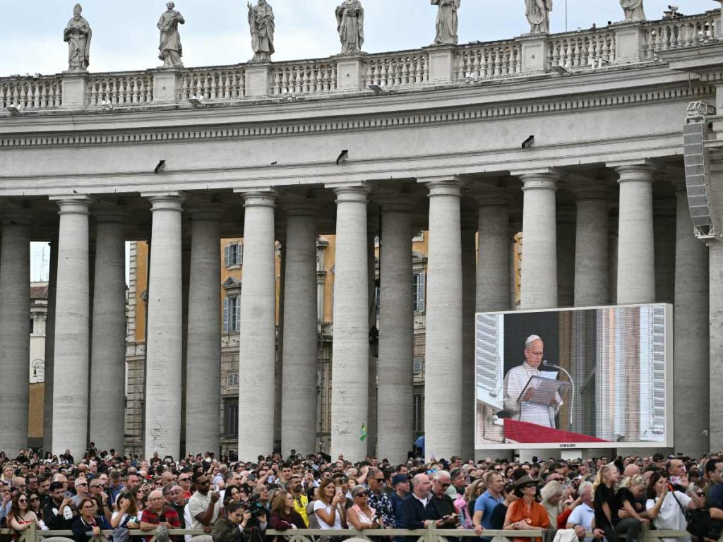 Varias personas escuchan al Papa León XIV en la Plaza de San Pedro durante el rezo del Ángelus, un día después de su regreso al Vaticano tras una operación para extirpar un tumor canceroso en su pulmón derecho, el 18 de octubre de 2026. (Foto de Tiziana FABI / AFP)
