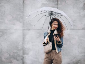 Young woman walking in the rain with umbrella